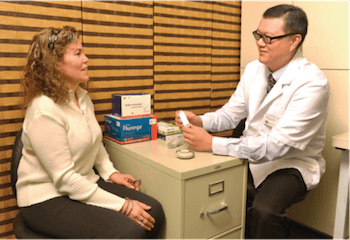 Dr. Tching conduzindo o aconselhamento com uma paciente sobre o uso correto de dispositivos inalatórios.