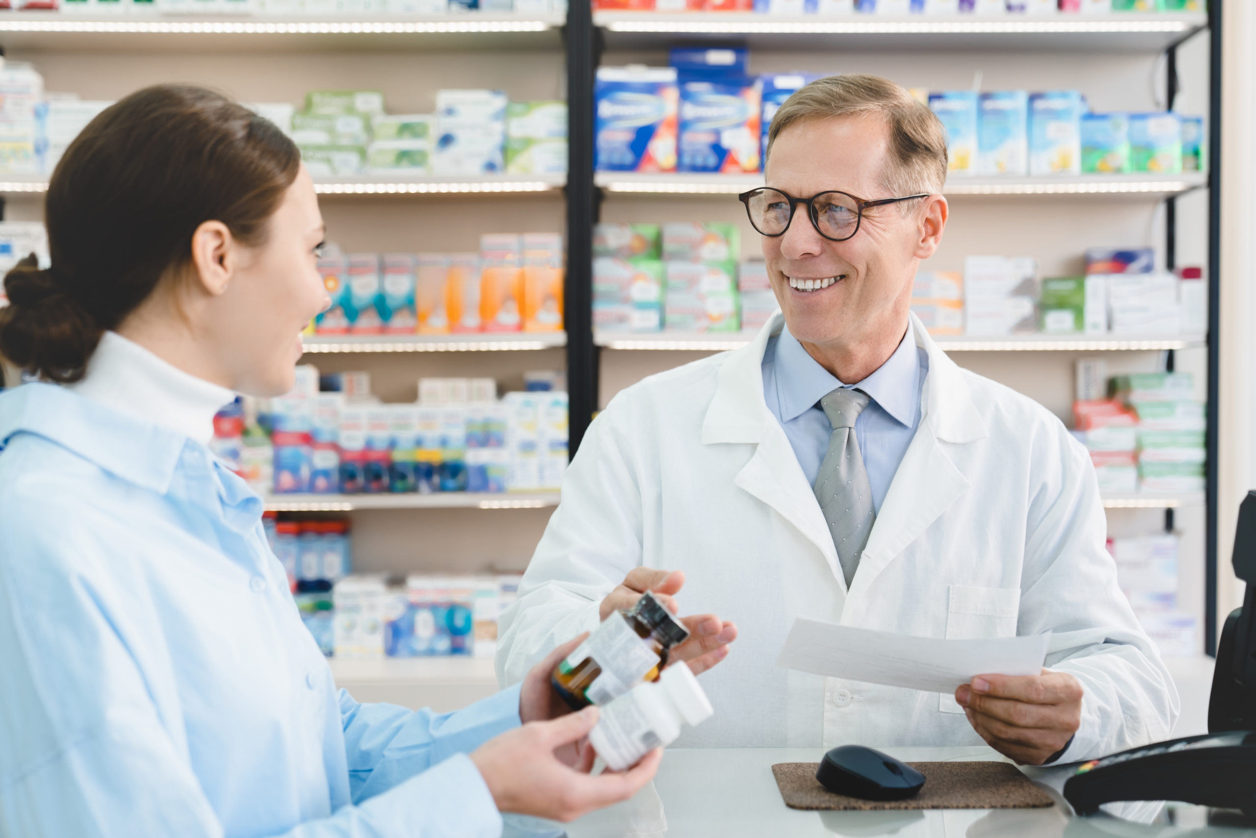 Pharmacist advising buyer remedy, medicines, pills, antibiotics holding prescription in pharmacy